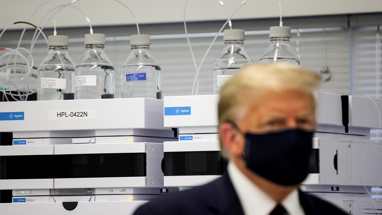 The photo shows the president wearing a mask in front of a fancy piece of equipment.