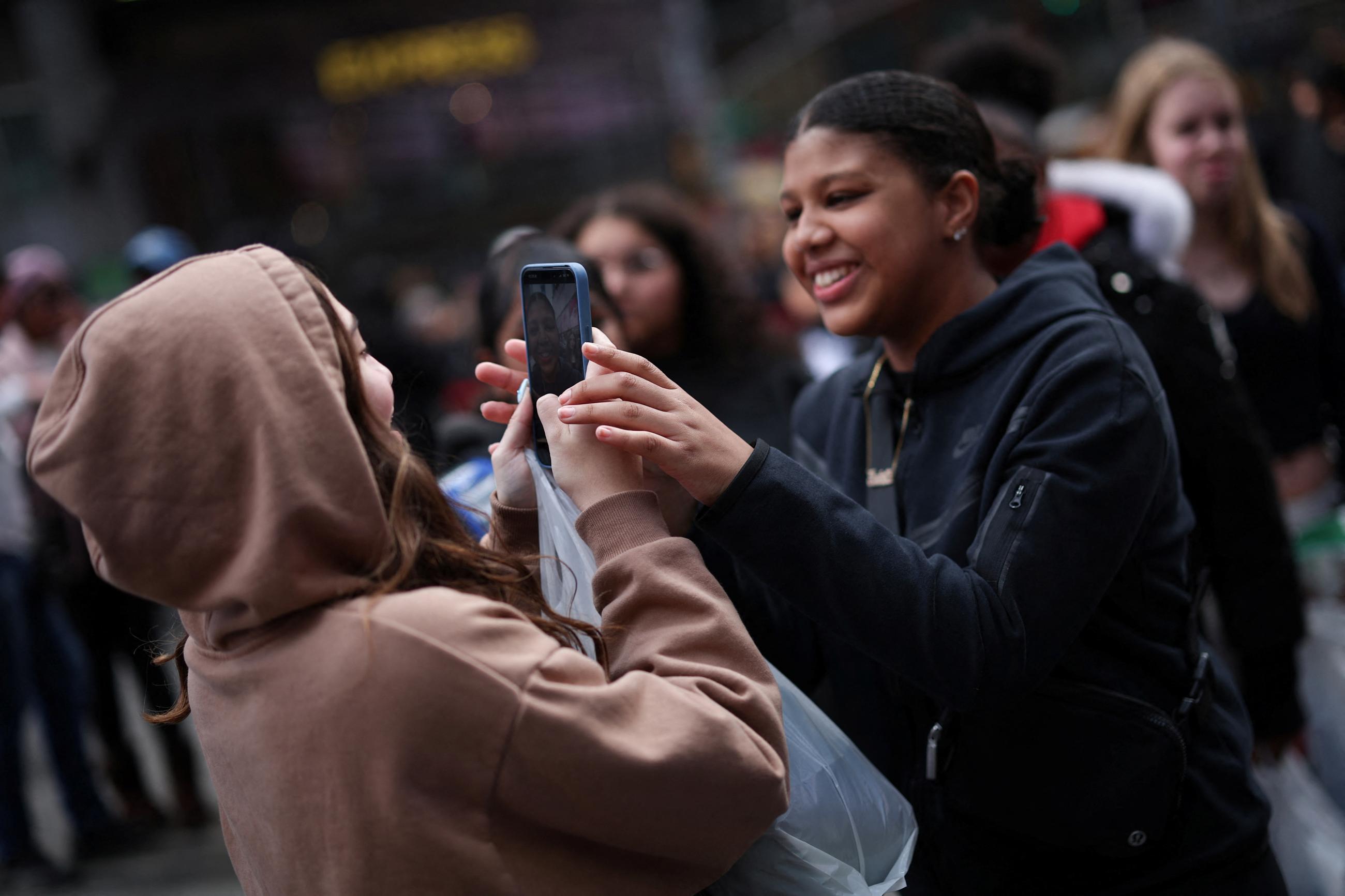 A young woman makes a video of her friends with a mobile phone to post on TikTok